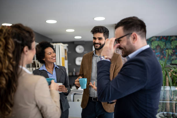 istock Group of smiling colleagues standing at workplace, chatting and drinking coffee on pause 1213035188