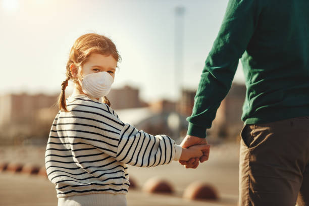 bambina in maschera medica che tiene per mano il padre - gender bender foto e immagini stock
