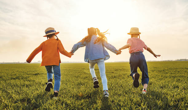 istock Anonymous happy children running backin field 1213037552