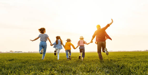 Anonymous happy family running back in field in summer evening