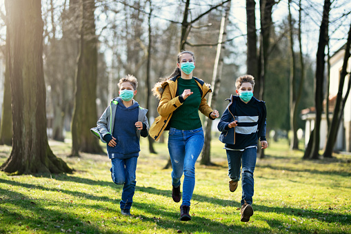 Three kids wearing anti virus masks. Kids are running in the park trying to enjoy the Spring despite the coronavirus outbreak.
Nikon D850