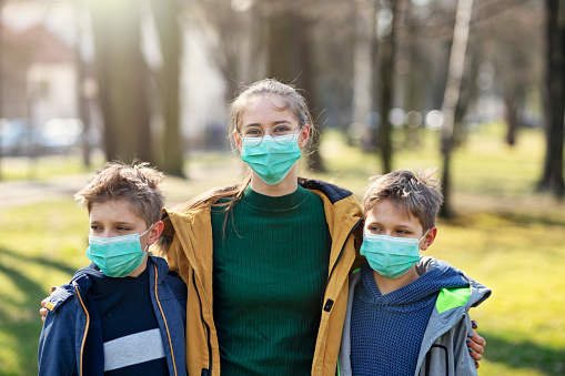 Three kids wearing anti virus masks. Kids are walking in the park trying to enjoy the Spring despite the coronavirus outbreak.
Nikon D850