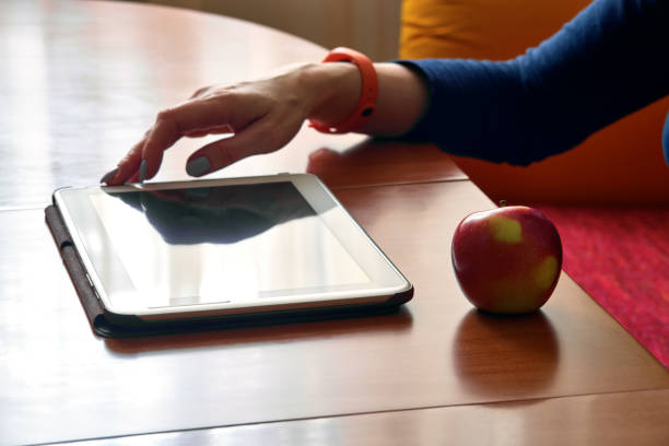 istock Red apple, hand and tablet at a shiny table, backlight, limited focus foreground 1213039566