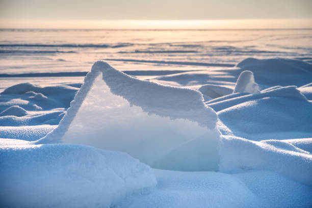 Transparent blue ice floes piled in ice hummocks against a blue sky on a sunny day. Unusual winter landscape of the frozen lake Baikal. Natural cold background. Siberia, Russia.