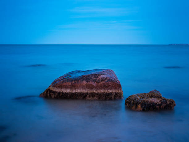 ニューイングランドのビーチの海岸近くに2つの大きな茶色の岩 - zen like sea horizon over water blurred motion ストックフォトと画像