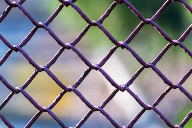 istock Metallic chain fence link net with blue defocused background 1213042575