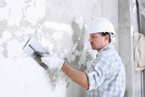 istock plasterer man at work with trowel plastering the wall of interior construction site wear helmet and protective gloves, isolated and copy space on white wall 1213044912