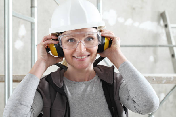 헬멧, 안전 안경 및 청력 보호 헤드폰을 착용한 미소 짓는 여성 노동자 초상화, 비계 내부 건설 현�장 배경 - protective eyewear safety glasses protection 뉴스 사진 이미지