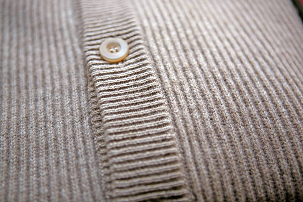 Blue knitted pullover with wooden buttons, close up. Wool yarn cardigan with brown buttons in sunlight. Cozy warm clothing. Handmade knitwear design. Knitted pattern close up. Autumn fashion.