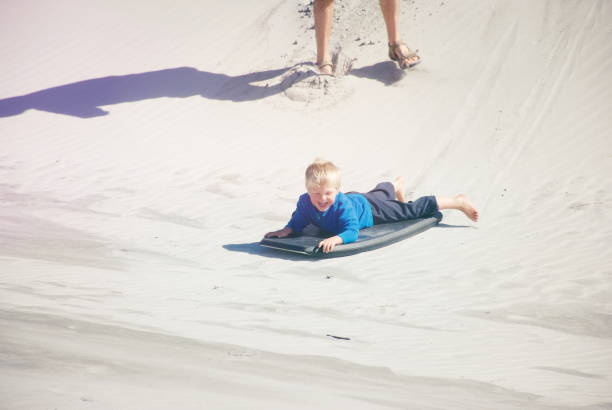 istock Child with Sand Board in Dunes 1213066977