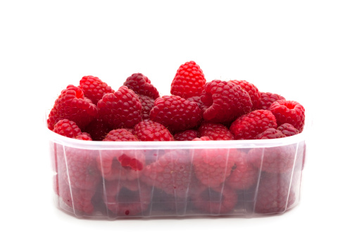 raspberries in plastic container on white background