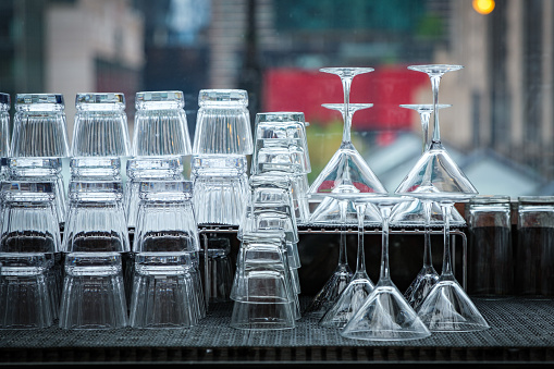 Close up of stacked shot glasses and martini glasses against a window.