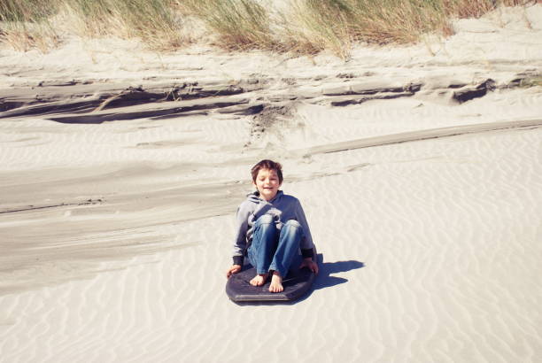 istock Child with Sand Board in Dunes 1213076315