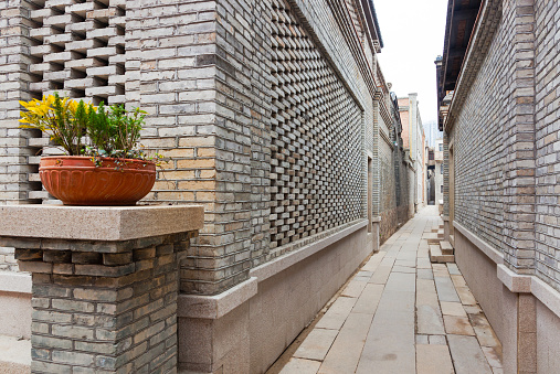 A characteristic alley of the retro style Chinese village, with brick houses and flagstone pavement, flower on pot decorated in entrance, Fuzhou,Fujian,China