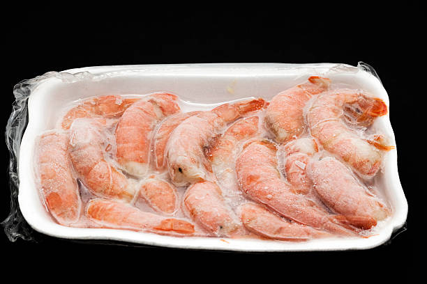 A white Styrofoam tray full of frozen shrimp  stock photo
