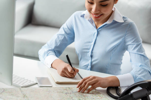 istock Tour agent sitting at table in office looking at map taking notes smiling cheerful close-up 1213087572