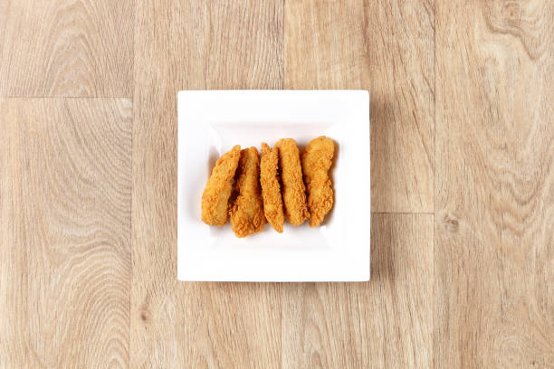 crispy chicken strips fingers crispy chicken strips fingers in a white plate on a wooden background top view chicken finger stock pictures, royalty-free photos & images