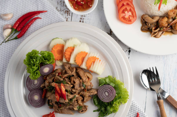 istock Stir fried pork basil on a white plate with carrots, Cucumber and Onion. Selective focus 1213100877