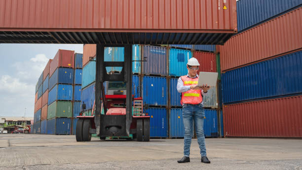 istock asian male containers cargo inspector working and containers yard and cargo with background of containers stack and container forklift 1213105171