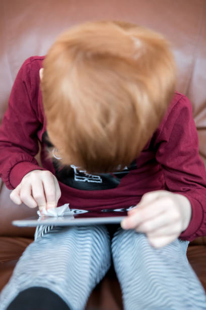 istock Young Boy cleaning display of digital tablet with antibacterial disposable wipes or tissue 1213105366