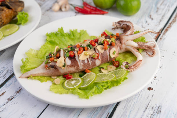 istock Spicy lemon squid with galangal, chilies, carrots, peppermint, spring onions and garlic on a plate on a white wooden floor. 1213106954