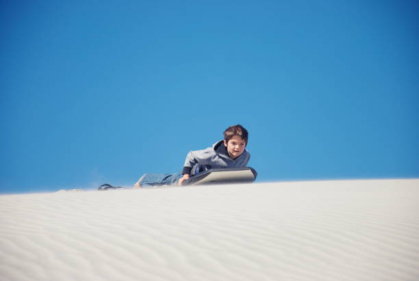 istock Child with Sand Board in Dunes 1213112249