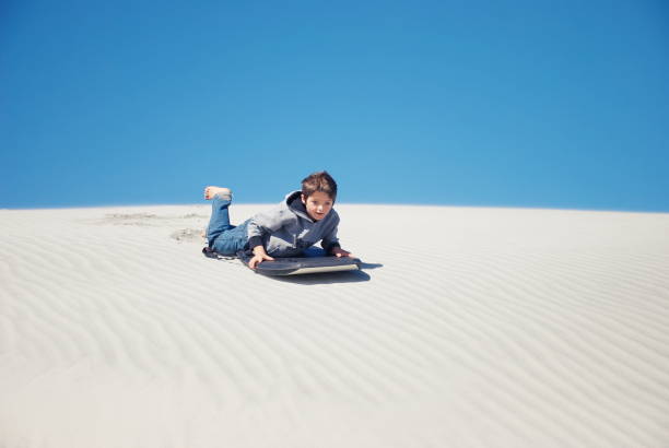istock Child with Sand Board in Dunes 1213112731