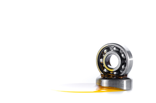 Closed up used ball bearing isolated on white background with copy space. Pouring automotive engine oil on ball bearing.