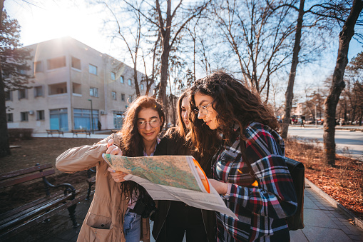 A group of young friends hikers in the fall, looking at the map and planning a walk