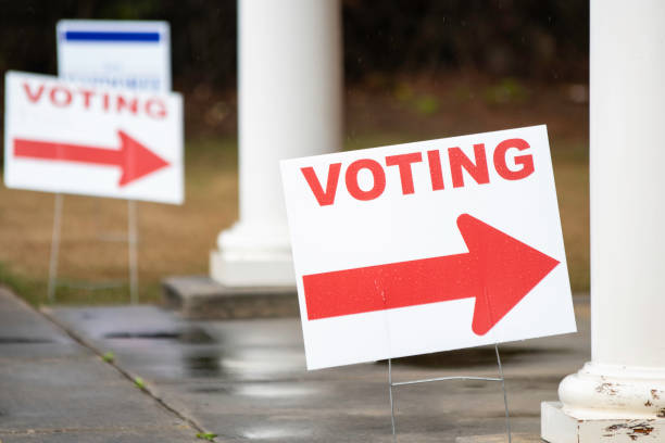 Voting Signs pointing to polling location in the rain Close up of voting signs pointing toward the polling location on a rainy day. primary election photos stock pictures, royalty-free photos & images
