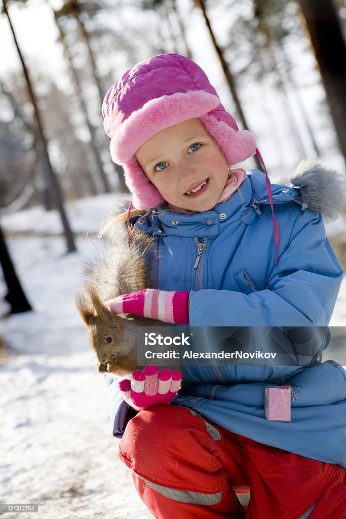 Una bambina alimentazione Scoiattolo nella foresta invernale. - Foto stock royalty-free di 6-7 anni