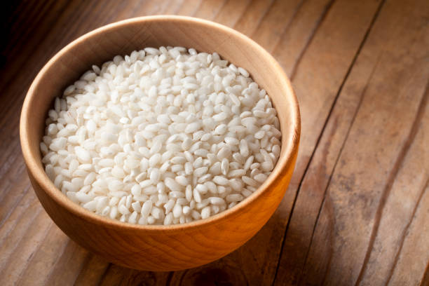 Carnaroli rice grains in wooden bowl.