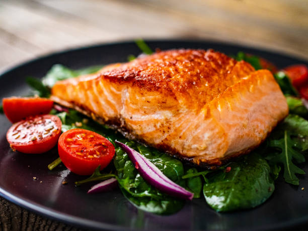 salmone fritto e verdure su sfondo legno - salmone arrosto foto e immagini stock