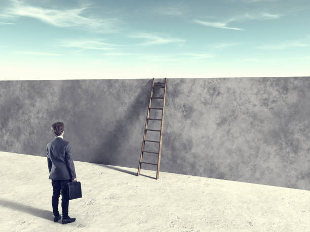 istock Businessman in front of ladder over a wall . Overcome obstacles and problems concept. 1213135438