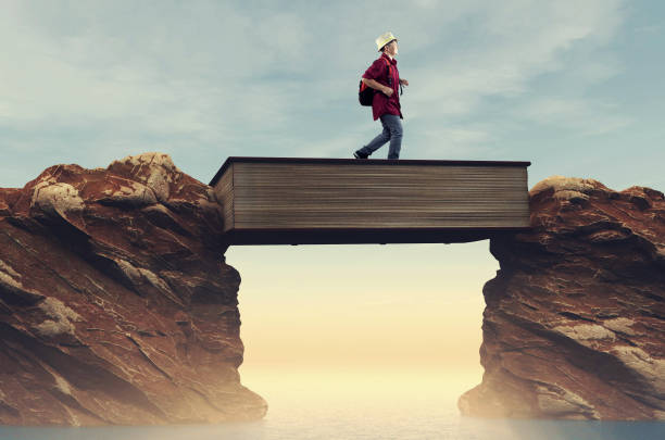 Student running over a gap between mountains on a book . Overcome any obstacle .