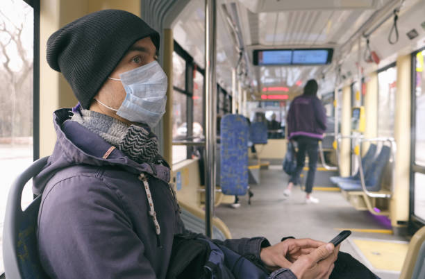 스마트 폰을 사용하여 대중 교통 트램 내부에 의료 보호 마스크와 장갑을 가진 성인 남자. 질병 발병, 코로나 바이러스 covid-19 전염병, 바이러스 보호, 대기 오염. - bus inside of people train 뉴스 사진 이미지
