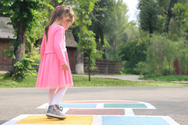 istock Young cute girl playing hopscotch on backyard 1213139063