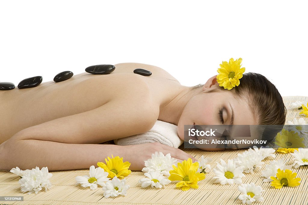 Spa salon: Kobieta relaksujący na mat z kwiatów i kamieni. - Zbiór zdjęć royalty-free (20-29 lat)