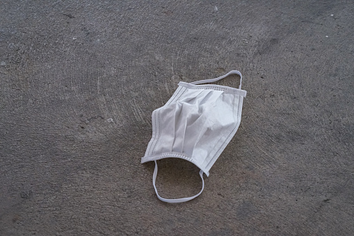 Allergy face mask were left on  concrete floor after people used to protect covid-19