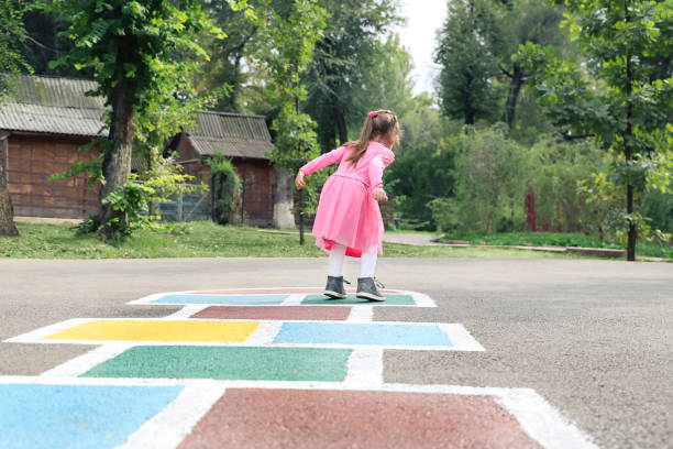 istock Young cute girl playing hopscotch on backyard 1213140283