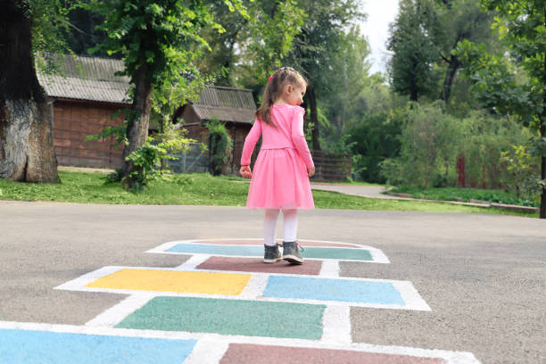 istock Young cute girl playing hopscotch on backyard 1213140432