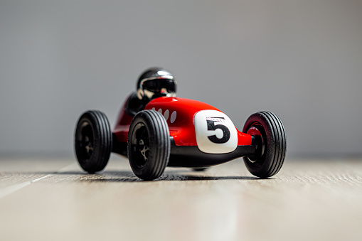 Red toy vintage racing car close up still with plate with number five painted on it