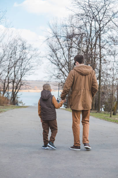 istock father with son walking by park holding hands 1213141595