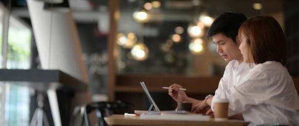 istock Side view of two businesspeople sitting in co-working space while discussing on their project 1213141651