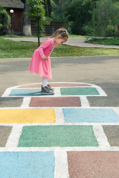 istock Young cute girl playing hopscotch on backyard 1213141786