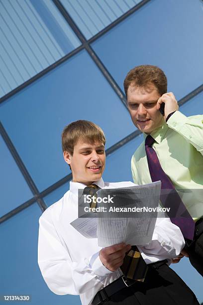 Dois Bem Sucedido Empresário Em Frente Das Janelas De Escritório Moderno - Fotografias de stock e mais imagens de A usar um telefone