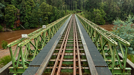 A steel bridge railway crossing over a creek on the route of the West Coast Wilderness Railway in Tasmania, Australia. Cinematic colour toning.