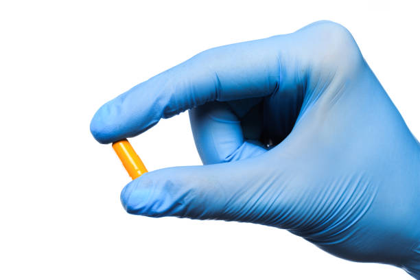 arzt hand in sterilen handschuhen halten pille isoliert auf weißem hintergrund nahansicht - surgical glove human hand holding capsule stock-fotos und bilder