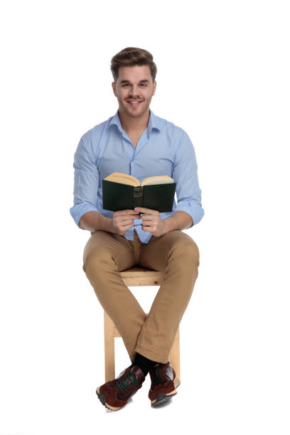 pozytywny przypadkowy człowiek czyta książkę i uśmiecha się - sitting young men book isolated on white zdjęcia i obrazy z banku zdjęć