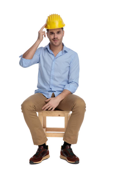 istock Bothered casual man pointing at his hard hat and frowning 1213152844
